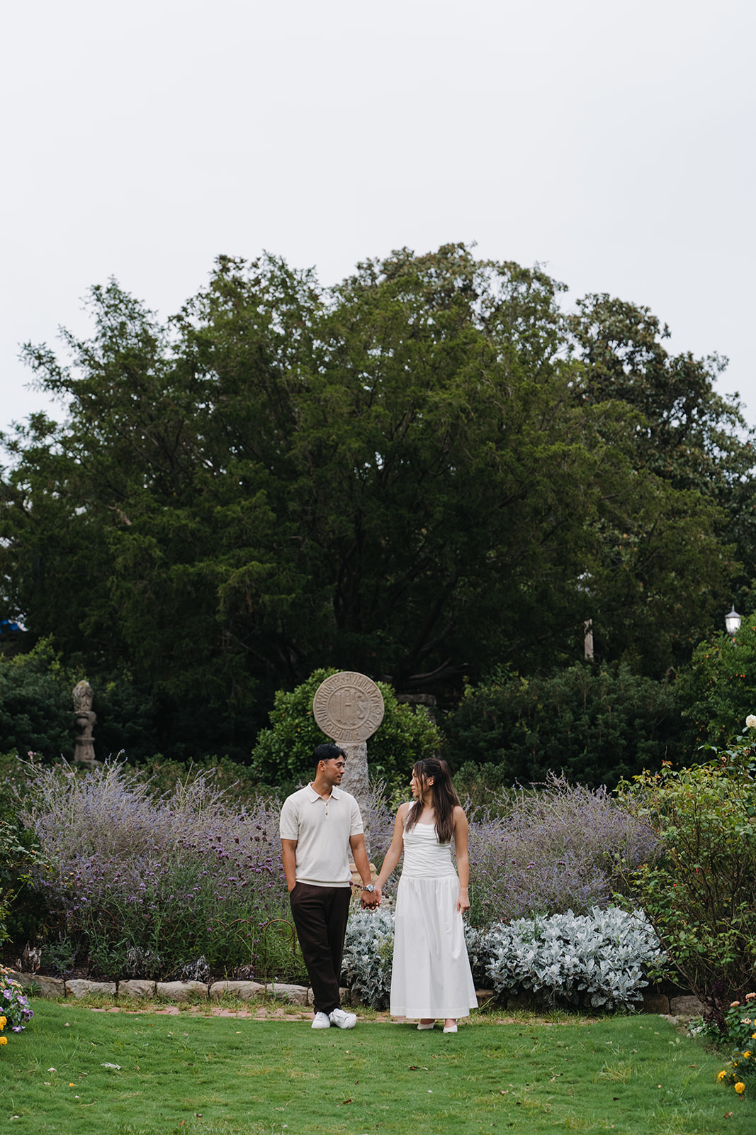 Andy and Jina holding hands on a garden lawn